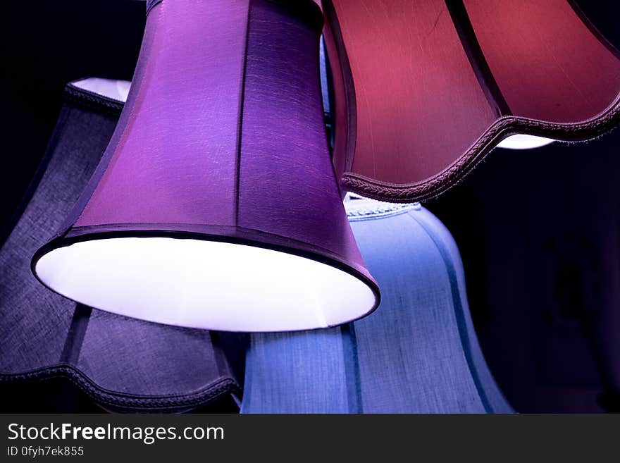 Set of colorful vintage lamp shades hung on dark background.