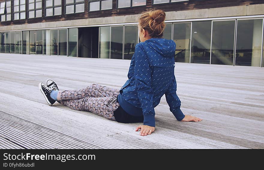 Trendy woman relaxing on decking in city with modern building in background.