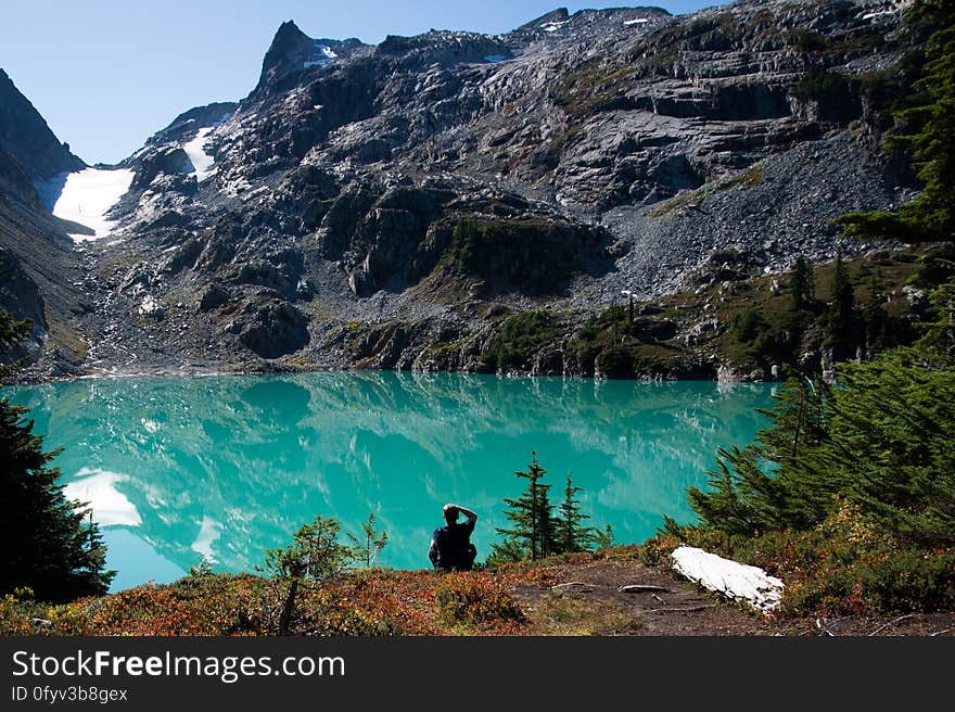 A person sitting next to the lake at mountains. A person sitting next to the lake at mountains.