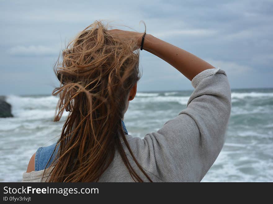 A woman standing by the sea with wind in her hair. A woman standing by the sea with wind in her hair.