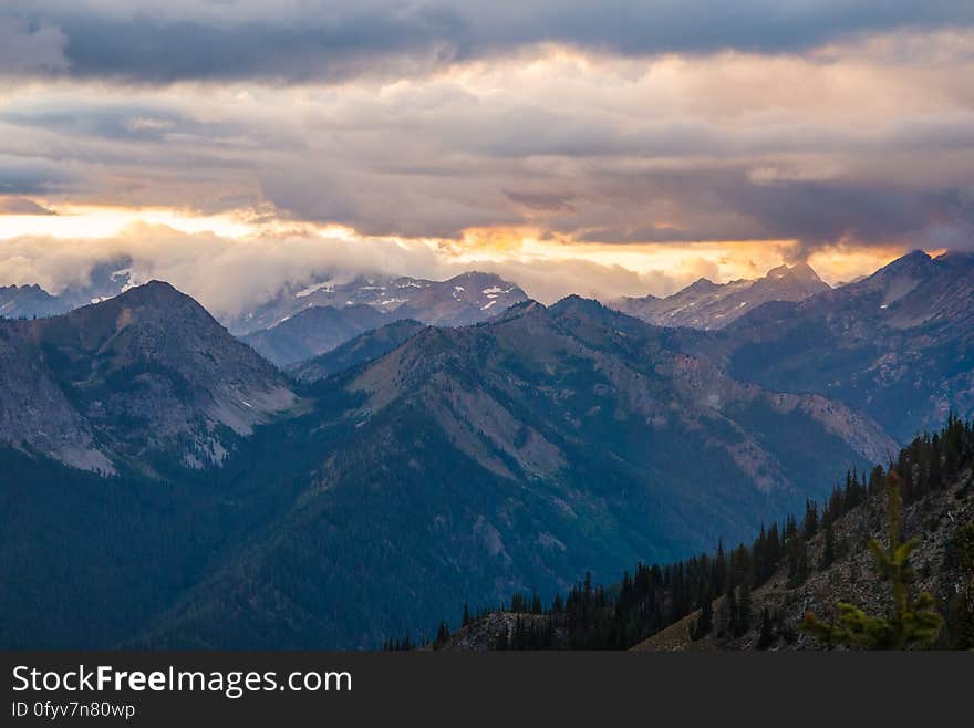 A mountain panorama with sun setting in the background.