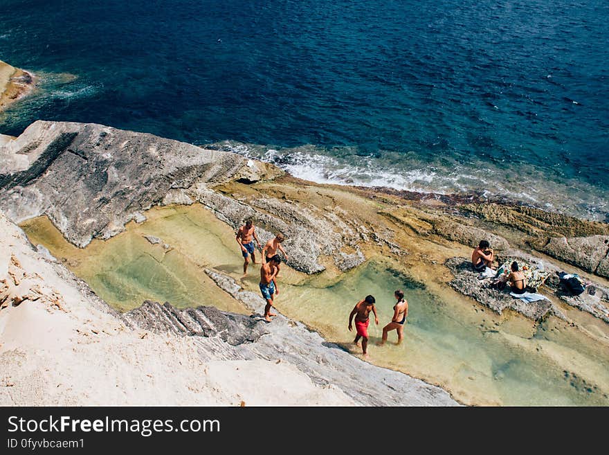 People relaxing on rocky beach on the island of Ibiza, Spain.