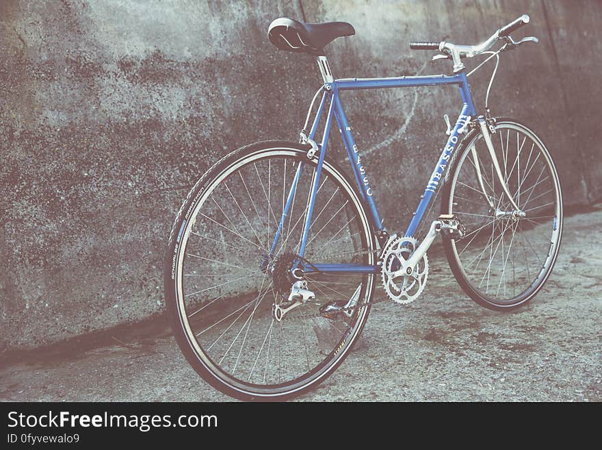 Blue bicycle leaning against cement wall on urban streets. Blue bicycle leaning against cement wall on urban streets.