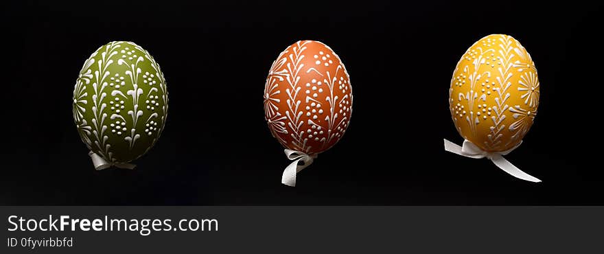 A trio of decorated Easter eggs on black background.