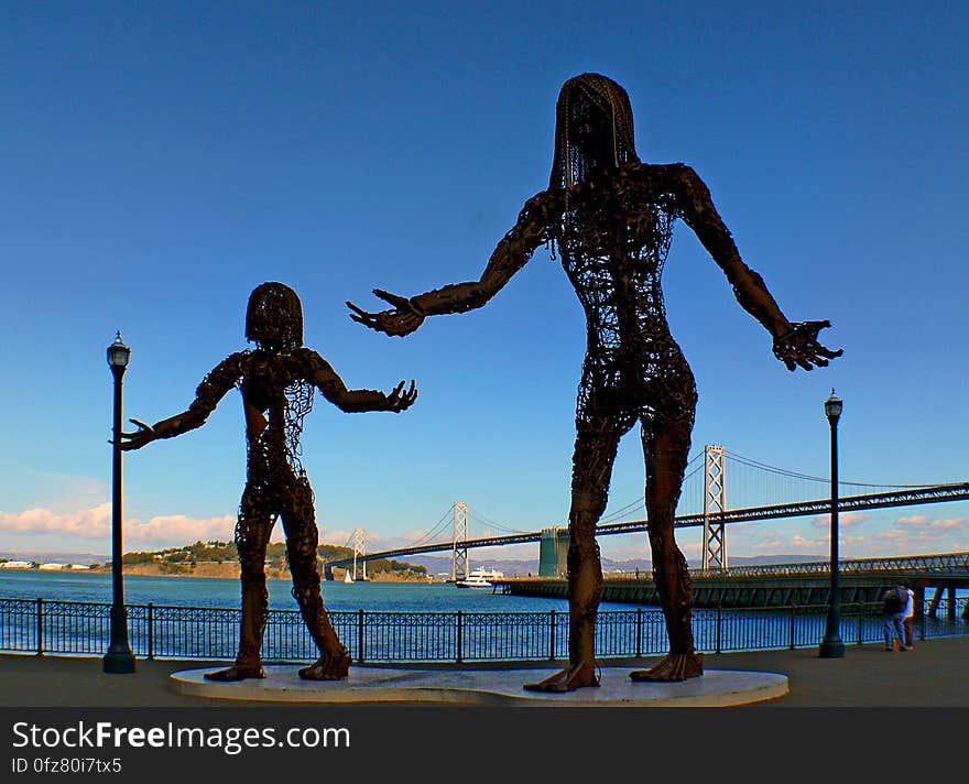 Gracing the waterfront of downtown San Francisco, this amazing display looks to be depicting a mother and daughter, with the much larger mother pouring something from her hand into the outstretched hand of her little girl. The statues have been constructed of metal, with both constructs composed of mostly empty air. While the family portrait is beautiful, the starkness of the metal and the cruelly formed hands give the display an almost dark and eerie look, depending on how you want to interpret the scene!. Gracing the waterfront of downtown San Francisco, this amazing display looks to be depicting a mother and daughter, with the much larger mother pouring something from her hand into the outstretched hand of her little girl. The statues have been constructed of metal, with both constructs composed of mostly empty air. While the family portrait is beautiful, the starkness of the metal and the cruelly formed hands give the display an almost dark and eerie look, depending on how you want to interpret the scene!