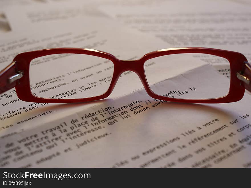 Red Framed Eyeglass on Top of Paper