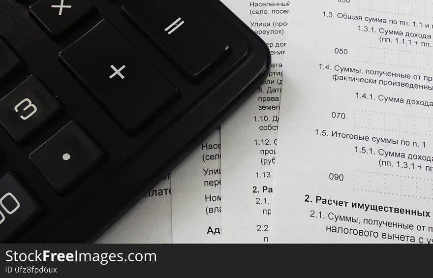 A close up of a calculator with papers on a table. A close up of a calculator with papers on a table.