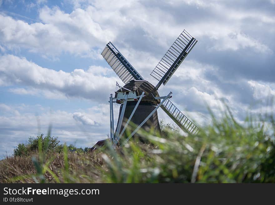 Windmill in grassy field against blue skies with clouds, Netherlands. Windmill in grassy field against blue skies with clouds, Netherlands.