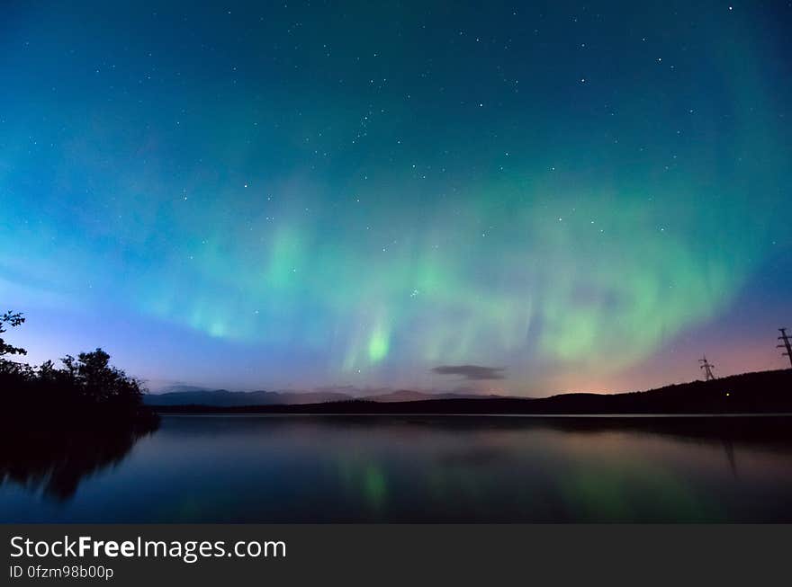 A view of a lake at night with the aurora on the sky. A view of a lake at night with the aurora on the sky.