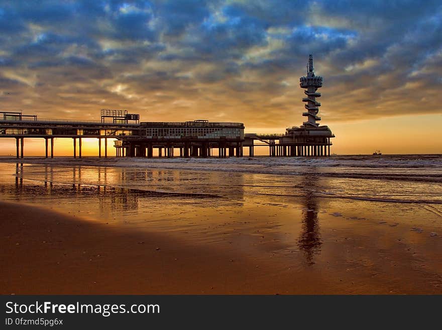 The sunrise on the sea with the silhouette of a pier on the beach. The sunrise on the sea with the silhouette of a pier on the beach.