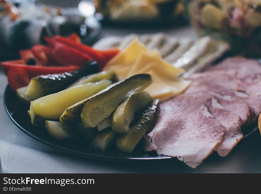 A plate of appetizers with pickles, meats, cheese and vegetables.