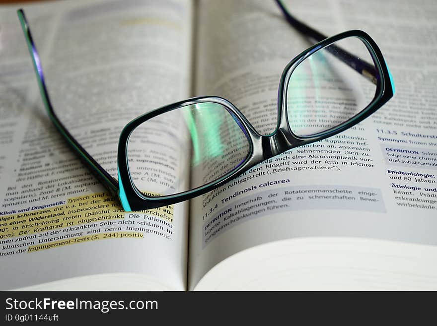 Close up of black frame glasses on open book with highlighter. Close up of black frame glasses on open book with highlighter.