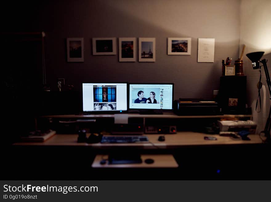 Computer desk in corner of dark room with two illuminated monitors. Computer desk in corner of dark room with two illuminated monitors.