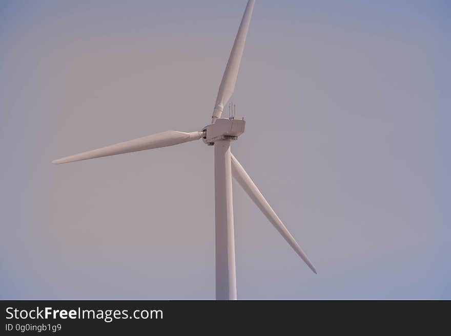 Closeup of the three blades of a green wind powered electricity generator, gray sky. Closeup of the three blades of a green wind powered electricity generator, gray sky.