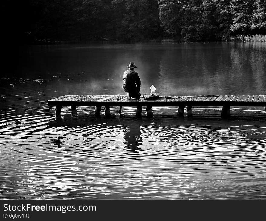 A black and white photo of a fisherman on a pier. A black and white photo of a fisherman on a pier.