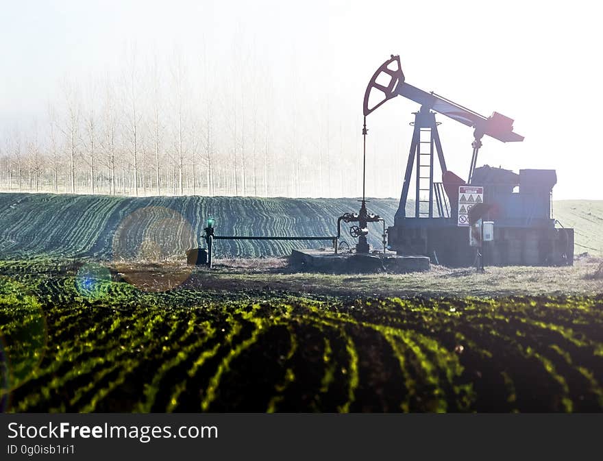 An oil pumpjack in the middle of a field. An oil pumpjack in the middle of a field.