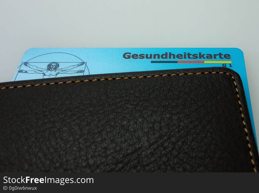 A health insurance business card sticking out of a leather wallet.