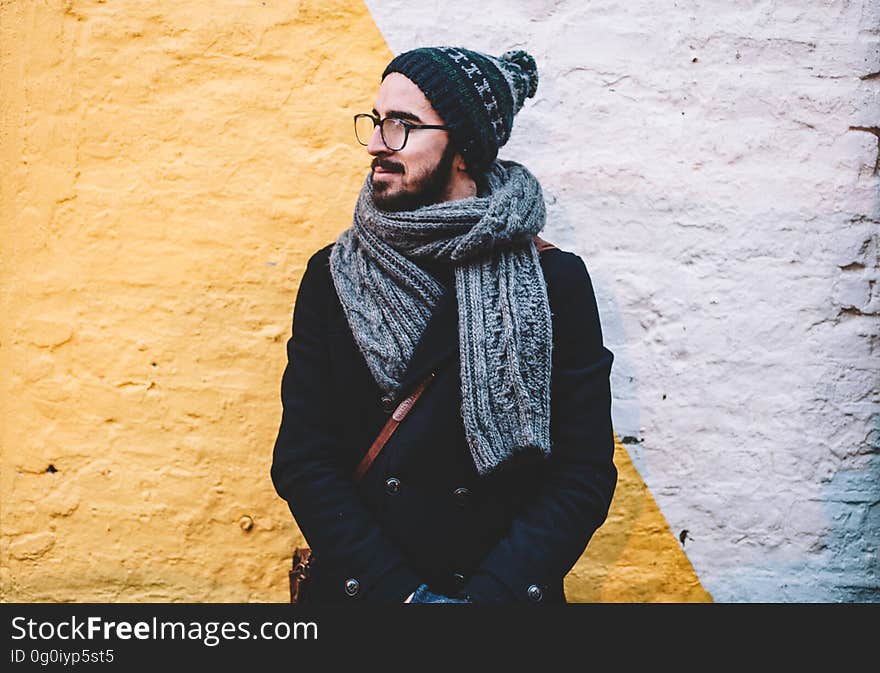 A young man with eyeglasses wearing a scarf and a cap. A young man with eyeglasses wearing a scarf and a cap.