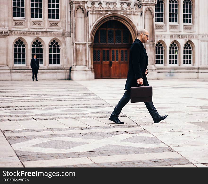 A businessman with a briefcase walking past a historic building. A businessman with a briefcase walking past a historic building.