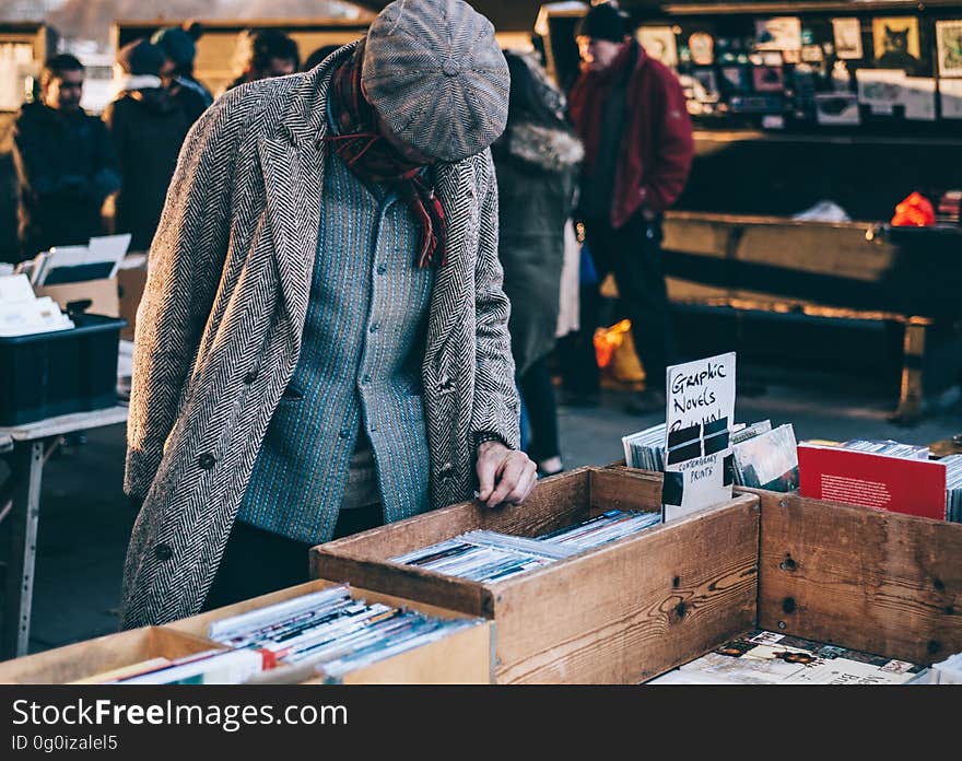 A man with a cap choosing books in a bookshop. A man with a cap choosing books in a bookshop.