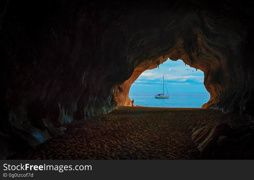 A view of a sailboat through an opening in a cave. A view of a sailboat through an opening in a cave.