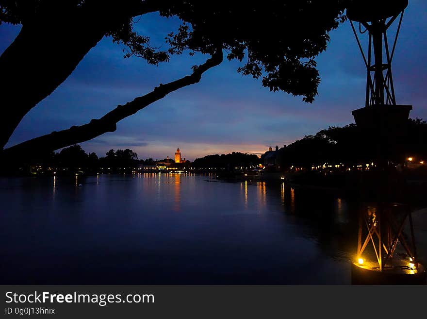 A sunset at a lake with buildings and lights reflecting on the surface. A sunset at a lake with buildings and lights reflecting on the surface.