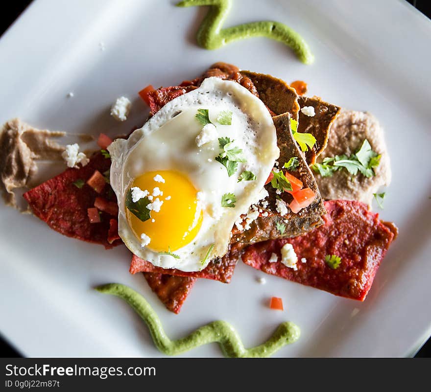 A plate with crisps and sauce with an egg on the top. A plate with crisps and sauce with an egg on the top.