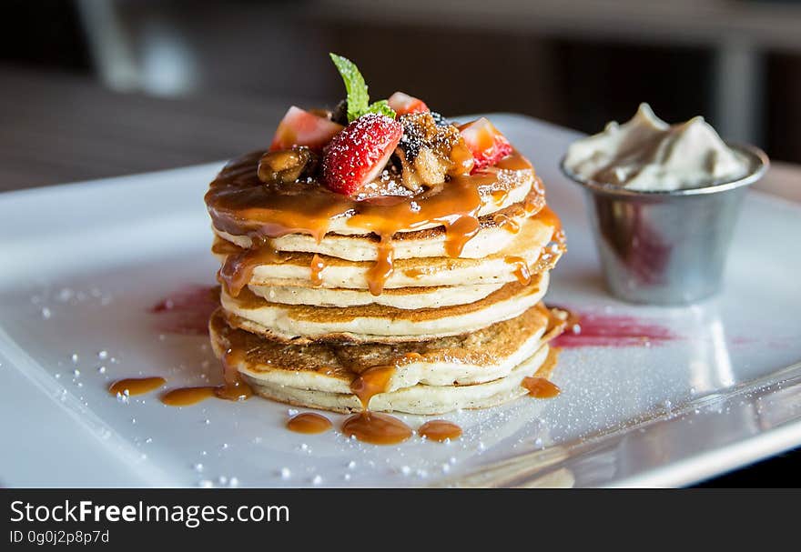 A stack of pancakes with caramel sauce and fresh fruits.