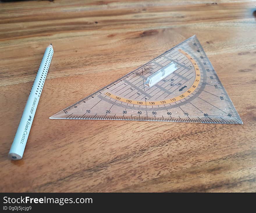 Geometric compass with triangular protractor on wooden desk.