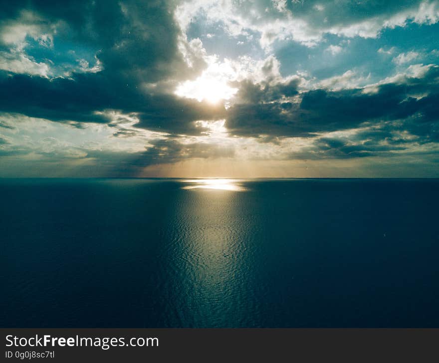 Sunrise with sun breaking through dramatic dark clouds and reflecting off the dark ocean. Sunrise with sun breaking through dramatic dark clouds and reflecting off the dark ocean.