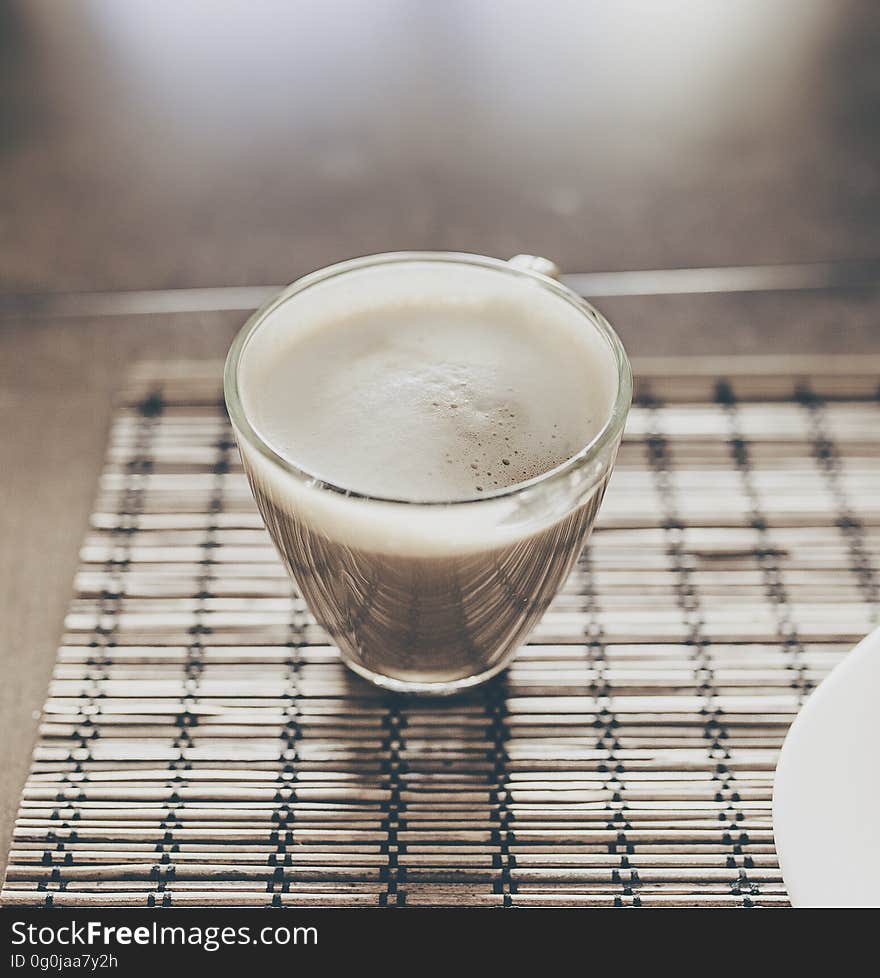 A cup of coffee with milk foam on a table. A cup of coffee with milk foam on a table.