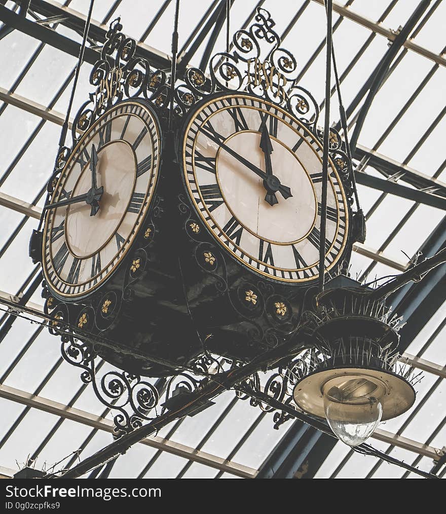 A vintage clock hanging from a glass ceiling.