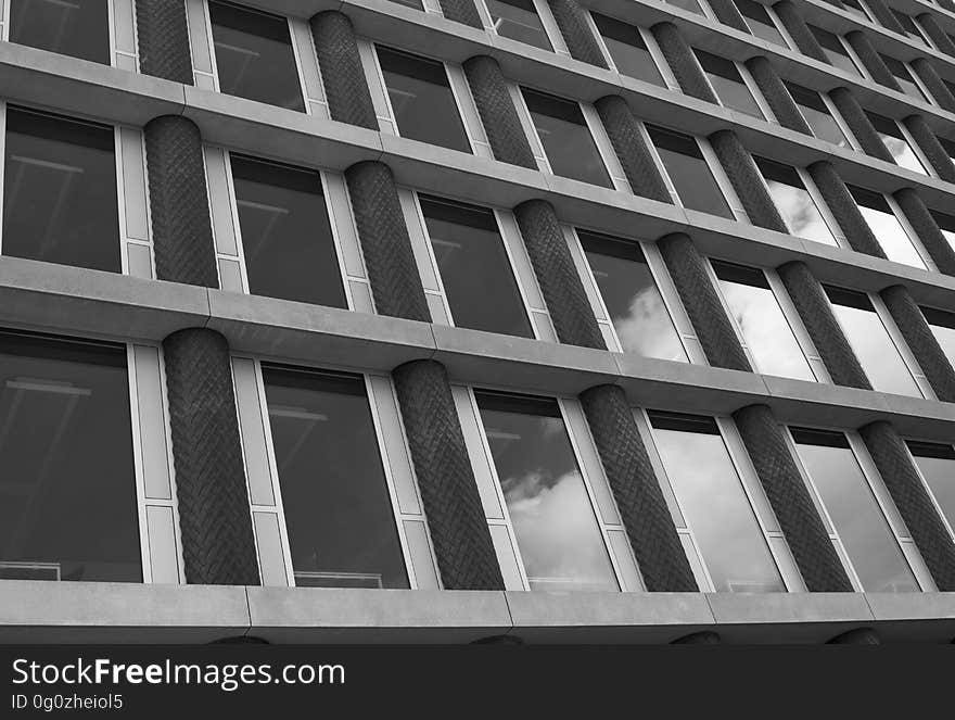 Background created by detail taken from large modern building comprising concrete lintels and glass windows and some windows showing reflection of a brighter sky. Background created by detail taken from large modern building comprising concrete lintels and glass windows and some windows showing reflection of a brighter sky.