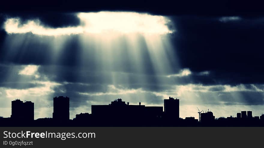 Crepuscular rays coming down from the clouds over a city.