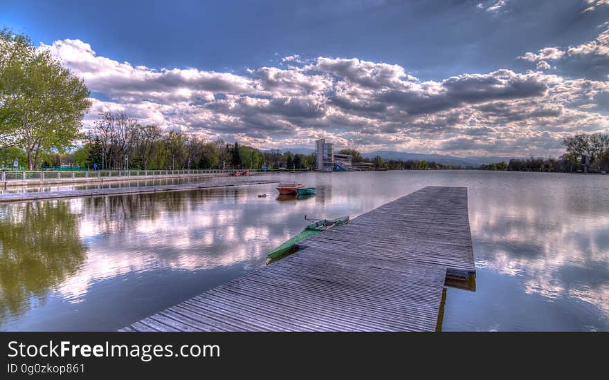 A wooden pier in the water with cloudy skies above. A wooden pier in the water with cloudy skies above.