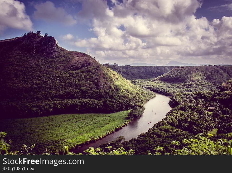 Elevated view of curving river in green valley next to mountain, cloudscape background. Elevated view of curving river in green valley next to mountain, cloudscape background.