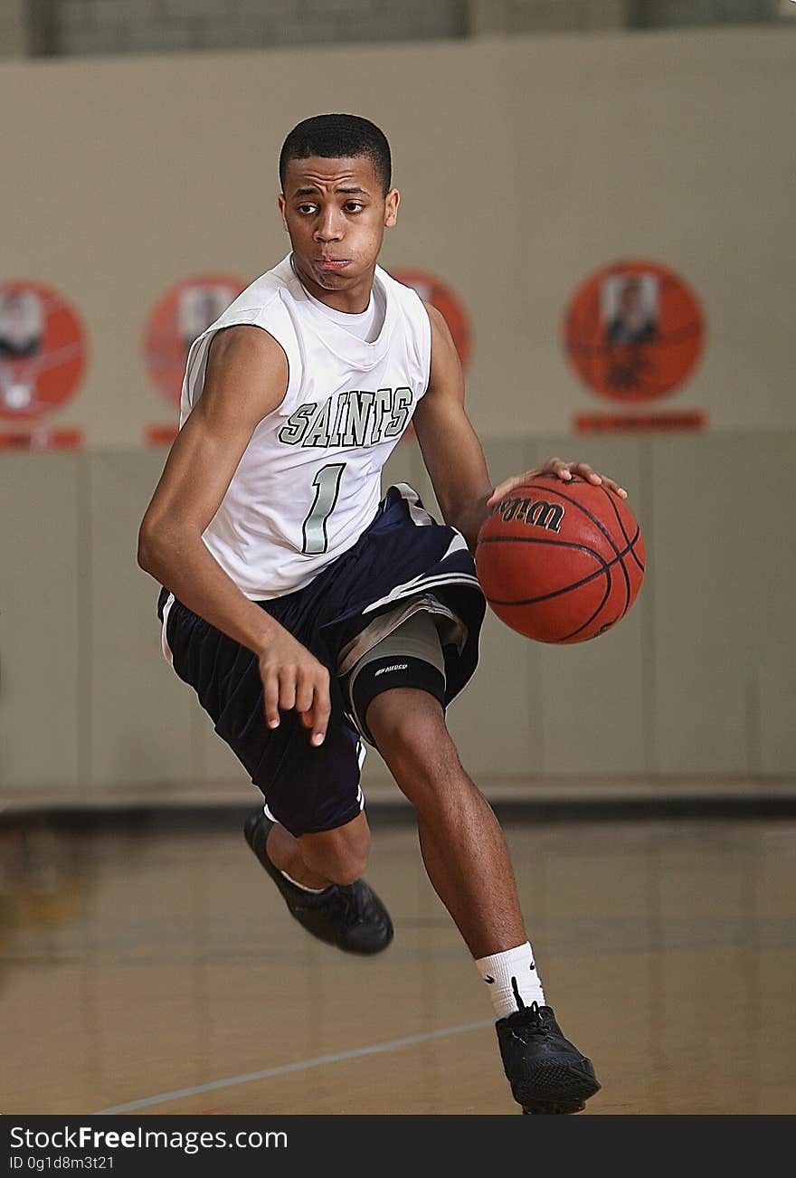 An African-American Basketball player dribbling the ball.