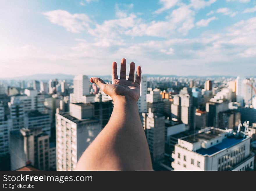 Distorted closeup of hand and arm with an urban cityscape background, in distance blue sky and thin cloud. Distorted closeup of hand and arm with an urban cityscape background, in distance blue sky and thin cloud.