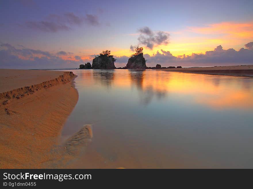 A sunrise or sunset on a sandy beach. A sunrise or sunset on a sandy beach.