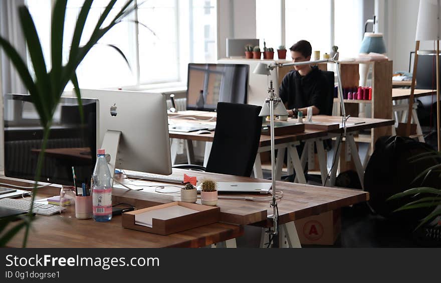 Old fashioned office space with windows, tables, bookshelves, papers, documents, bottled water and one man working at his desk. Old fashioned office space with windows, tables, bookshelves, papers, documents, bottled water and one man working at his desk.