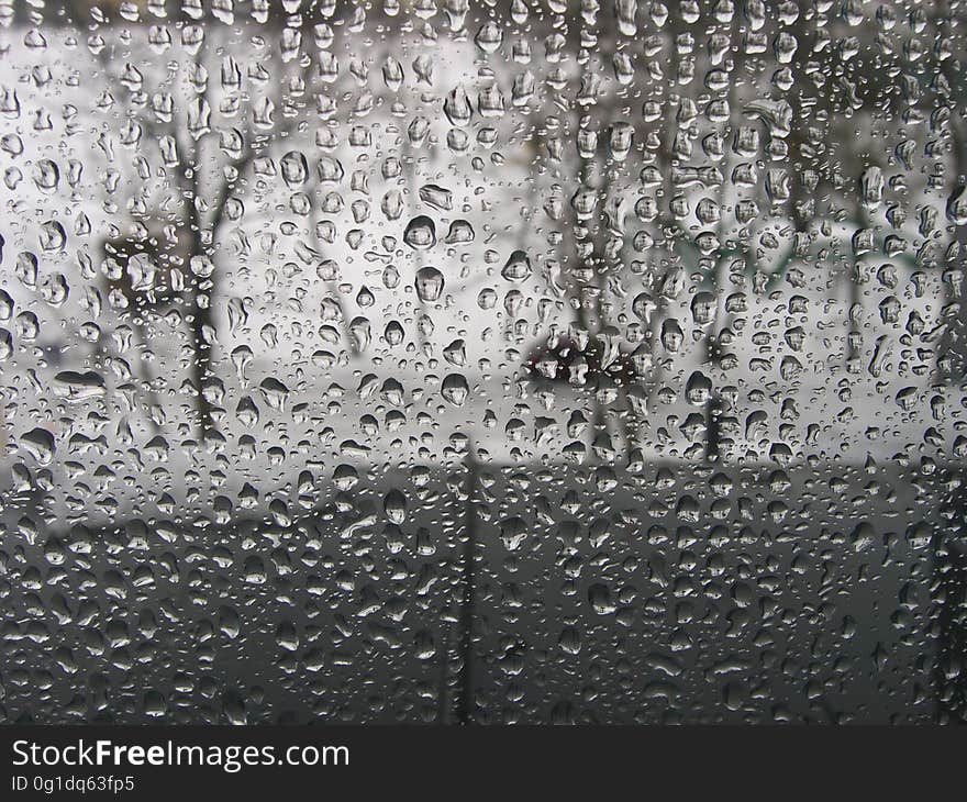 Raindrops on window pane allowing only blurred image of trees (in park) beyond.