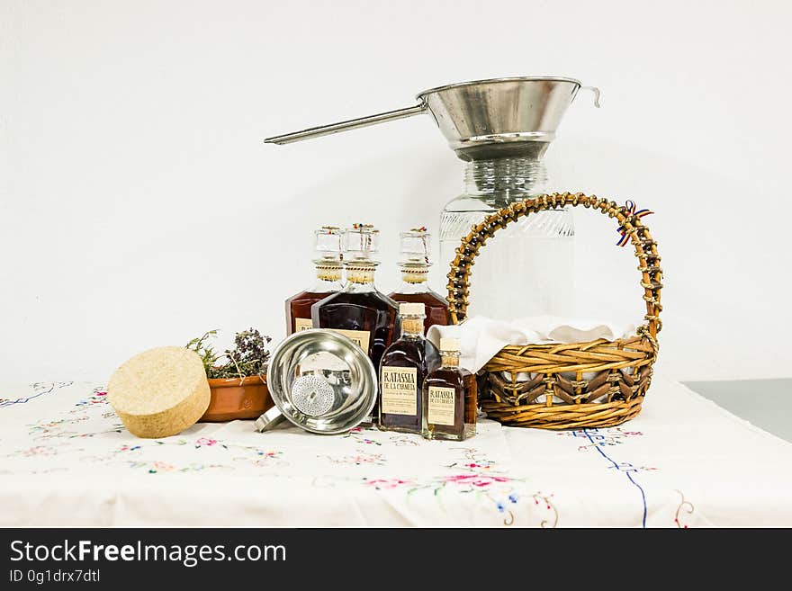 Brown Woven Basket Beside Clear Bottle on White Table Clothe