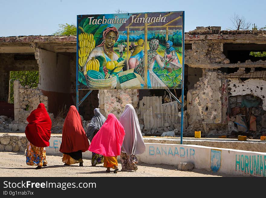 Somali woman walk past a billboard mural saying “Cultivate to prosper” that was displayed as part of a project to produce and display billboards around Mogadishu designed to mobilise and educate people through art to better understand and absorb the differences, benefits and realities between conflict and peace. During the occupation of the city by the Al-Qaeda-affiliated militant group Al Shabaab up until August 2011, many Somali artists were either forced to work in secret or stop practising their art all together for fear of retribution and punishment by the extremist group who were fighting to overthrow the internationally-recognised then transitional government and implement a strict and harsh interpretation of Islamic Sharia law. After 20 years of near-constant conflict, Mogadishu and large areas of Somalia are now enjoying the longest period of peace in years after sustained military operations by the Somali National Army &#x28;SNA&#x29; backed by the forces of the African Union Mission in Somalia &#x28;AMISOM&#x29; forced Al Shabaab to retreat from many areas of the country precipitating something of a renaissance for Somali artists and business, commerce, sports and civil liberties and freedoms flourishing once again. AU-UN IST PHOTO / STUART PRICE. Somali woman walk past a billboard mural saying “Cultivate to prosper” that was displayed as part of a project to produce and display billboards around Mogadishu designed to mobilise and educate people through art to better understand and absorb the differences, benefits and realities between conflict and peace. During the occupation of the city by the Al-Qaeda-affiliated militant group Al Shabaab up until August 2011, many Somali artists were either forced to work in secret or stop practising their art all together for fear of retribution and punishment by the extremist group who were fighting to overthrow the internationally-recognised then transitional government and implement a strict and harsh interpretation of Islamic Sharia law. After 20 years of near-constant conflict, Mogadishu and large areas of Somalia are now enjoying the longest period of peace in years after sustained military operations by the Somali National Army &#x28;SNA&#x29; backed by the forces of the African Union Mission in Somalia &#x28;AMISOM&#x29; forced Al Shabaab to retreat from many areas of the country precipitating something of a renaissance for Somali artists and business, commerce, sports and civil liberties and freedoms flourishing once again. AU-UN IST PHOTO / STUART PRICE.