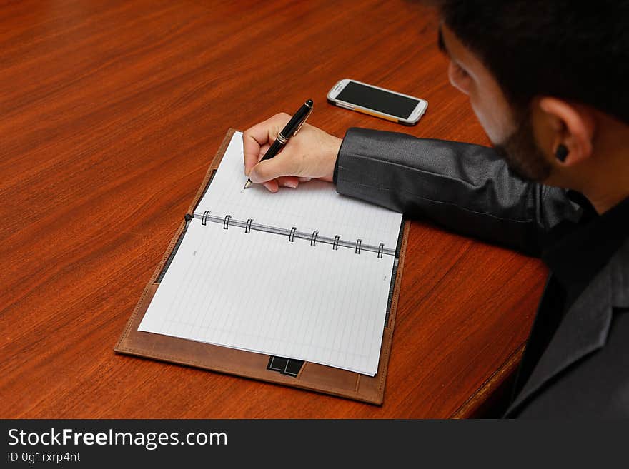 A man writing on his notebook. A man writing on his notebook.