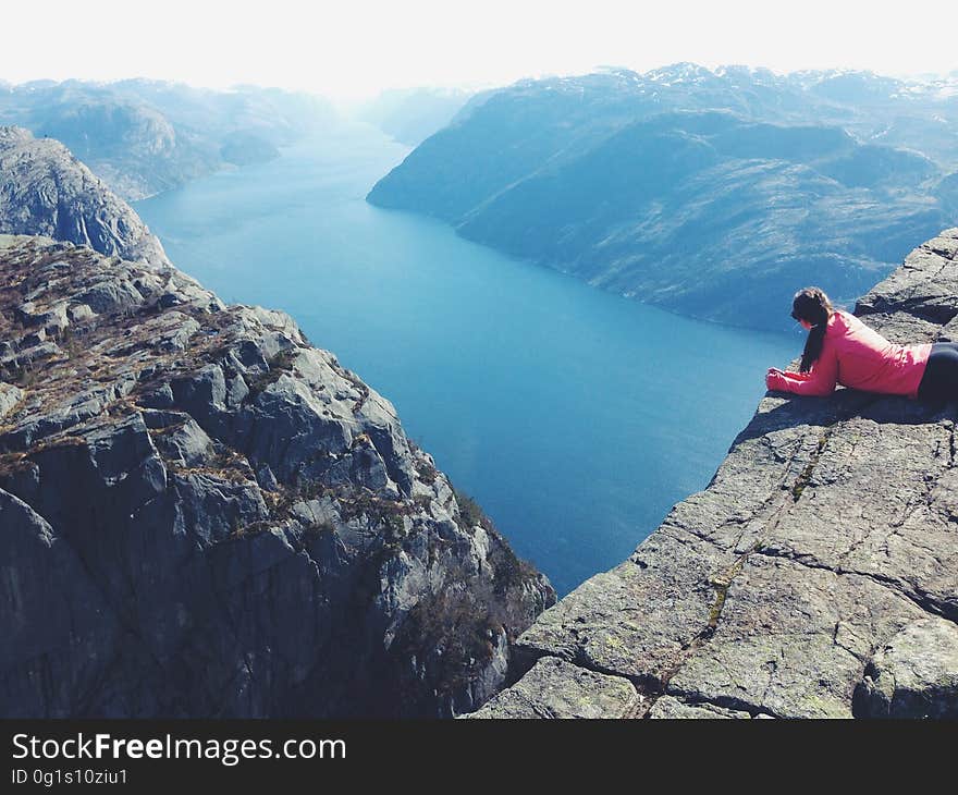 A woman looking down at the fjord at Preikestolen in Norway. A woman looking down at the fjord at Preikestolen in Norway.