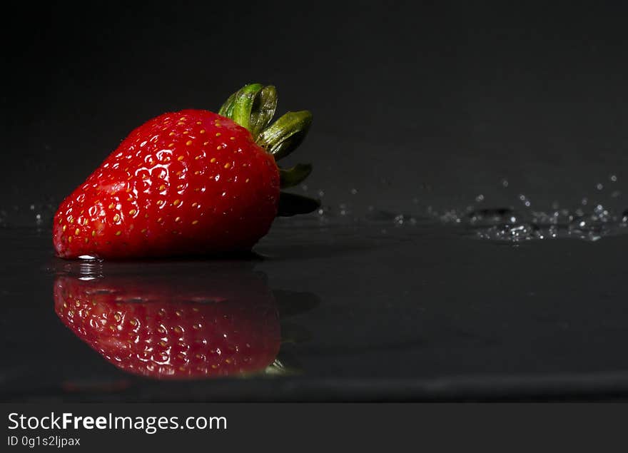 A close up of a red strawberry fruit on dark background.