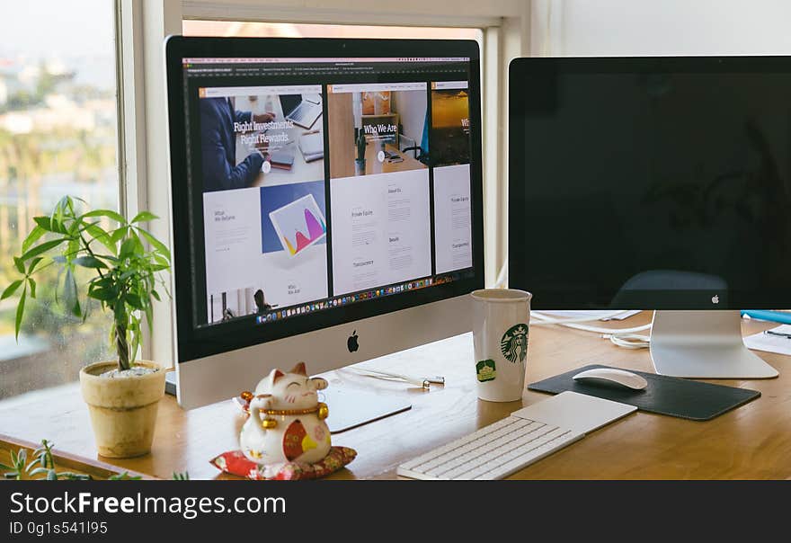 A workstation with two computers and potted plant. A workstation with two computers and potted plant.