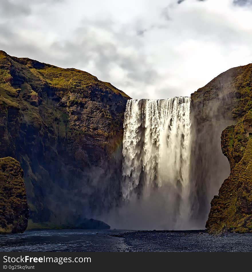 A cliff with waterfall cascading down into a pool. A cliff with waterfall cascading down into a pool.