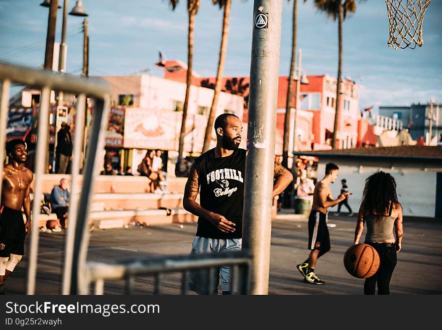 A basketball court on the beach with people.