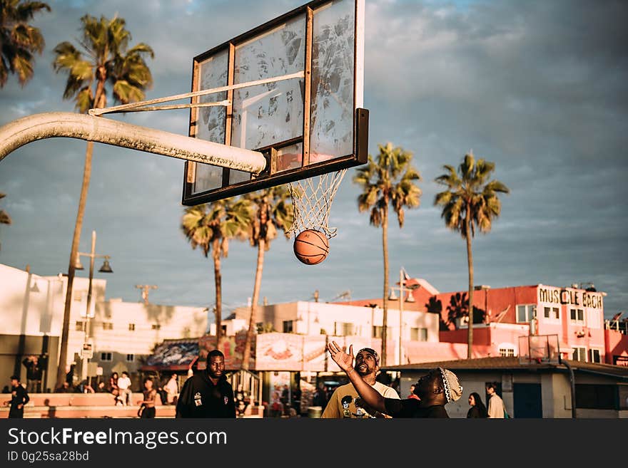 A basketball court on the beach with players shooting hoops. A basketball court on the beach with players shooting hoops.